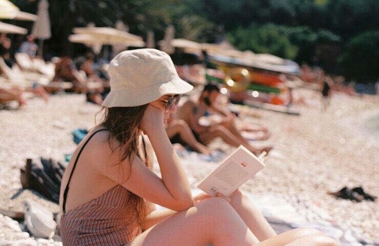 ragazza con libro aperto legge in spiaggia