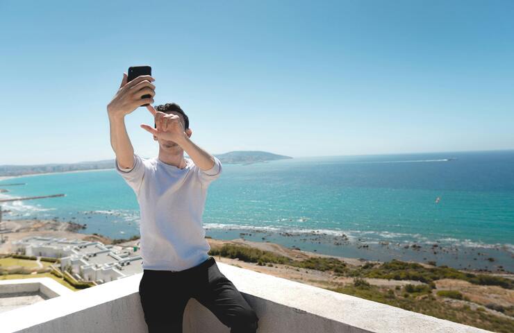 ragazzo si scatta selfie con sfondo al mare